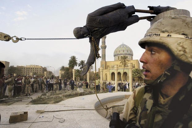 Iraqi civilians and U.S. soldiers pull down a statue of Saddam Hussein in downtown Baghdad