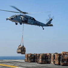helicopter lifting cargo from aircraft carrier